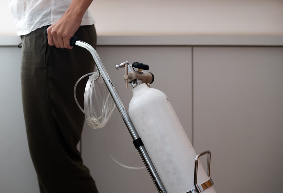 Woman is holding portable oxygen gas cylinder for use at home.